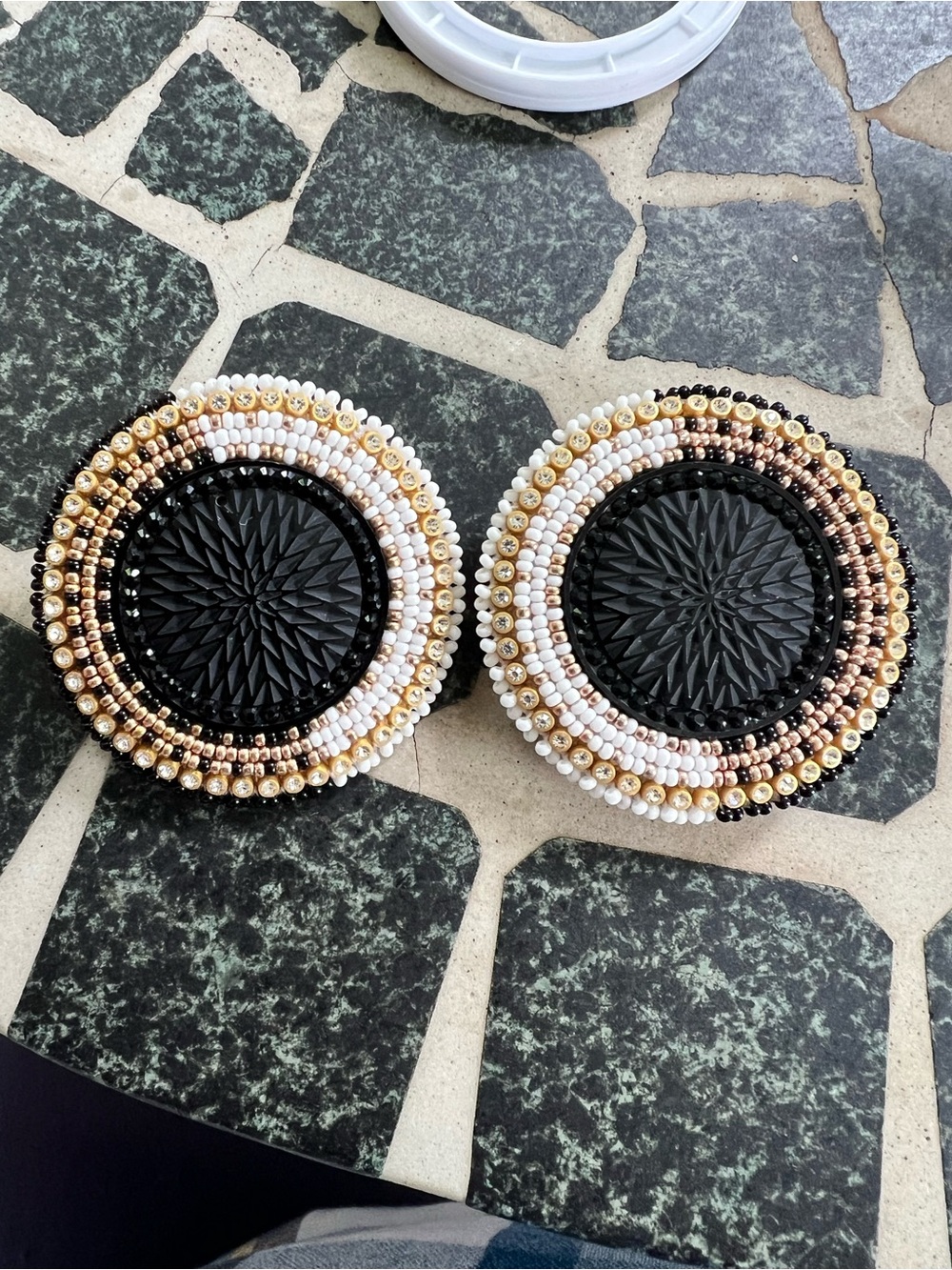 Handmade beaded disks with leather backs and post closure. 2” diameter